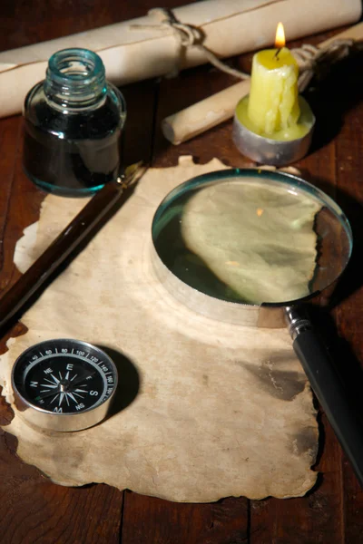 Vecchia carta con penna inchiostro e lente d'ingrandimento vicino alla candela di illuminazione su tavolo di legno — Foto Stock