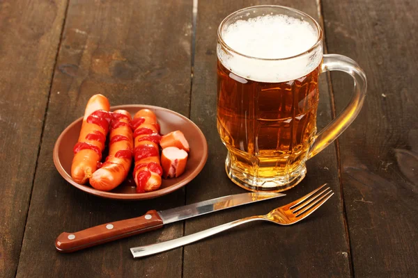Пиво и колбасы на деревянном фоне — стоковое фото