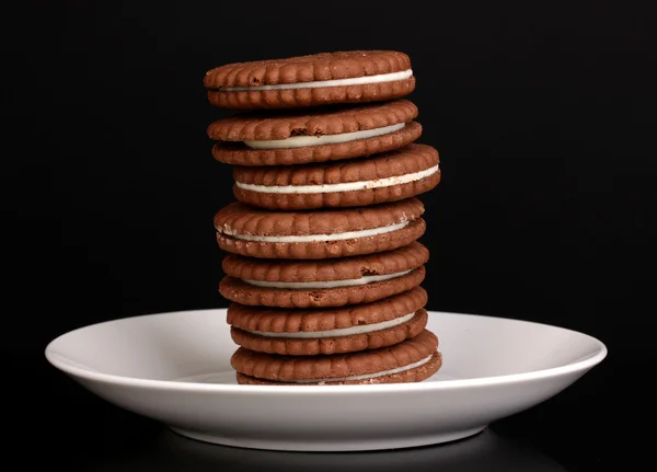 Chocolade koekjes met romige laag op plaat geïsoleerd op zwart — Stockfoto