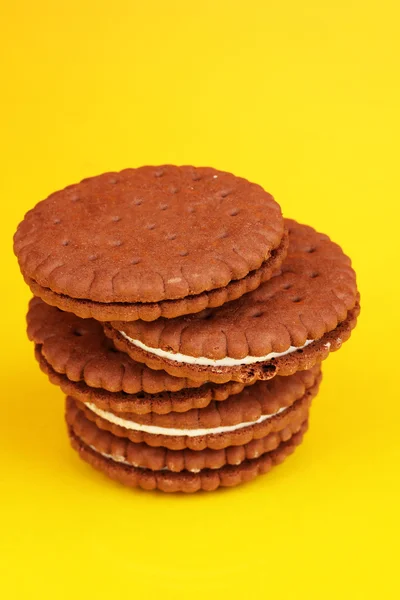 Biscotti al cioccolato con strato cremoso su sfondo giallo — Foto Stock