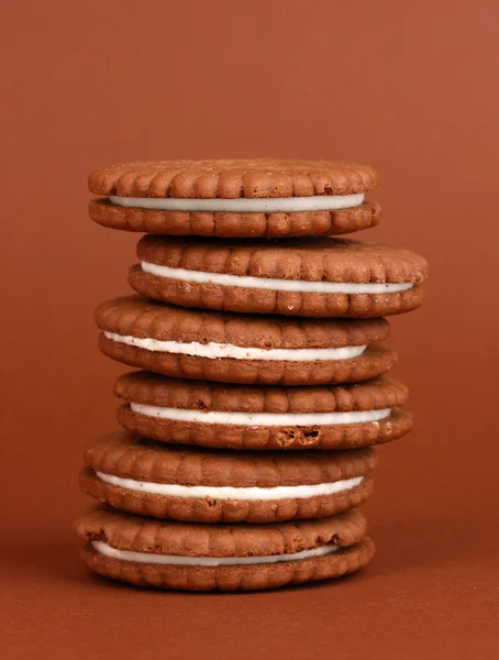 Čokoládové cookies s krémovou vrstvu na hnědé pozadí — Stock fotografie
