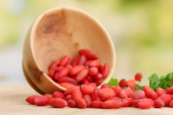 Barberries maduras em tigela de madeira com folhas verdes, na mesa — Fotografia de Stock