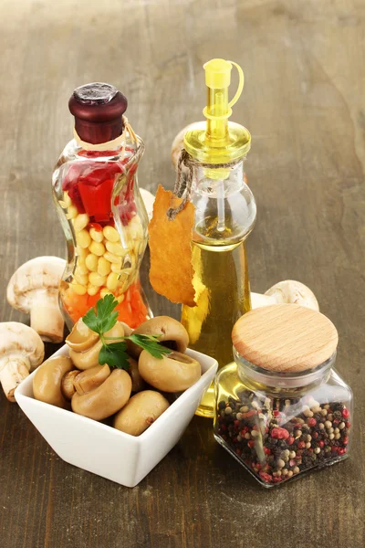 Delicious marinated mushrooms in bowl with spices on wooden table — Stock Photo, Image