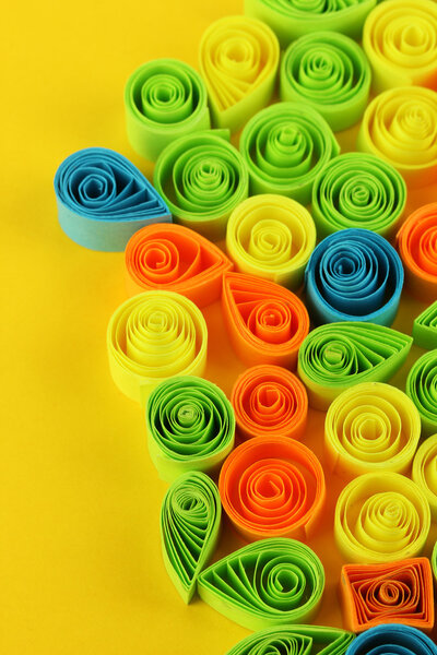 Colorful quilling on yellow background close-up