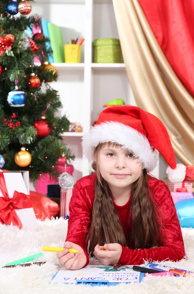 Beautiful little girl writes letter to Santa Claus in festively decorated room Stock Photo