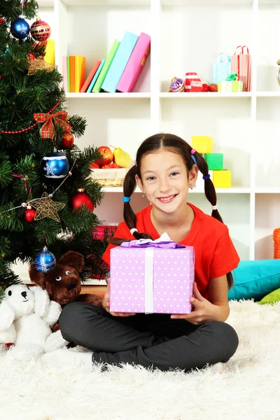 Little girl holding gift box near christmas tree Royalty Free Stock Photos