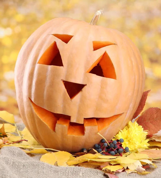 Halloween pumpkin and autumn leaves, on yellow background — Stock Photo, Image