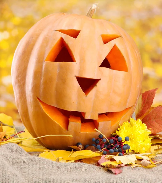 Zucca di Halloween e foglie autunnali, su sfondo giallo — Foto Stock