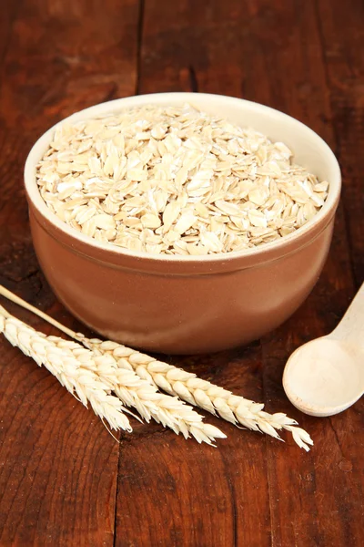 Oat flakes in brown bowl on the table — Stock Photo, Image