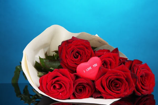 Beautiful bouquet of red roses with valentine on blue background — Stock Photo, Image