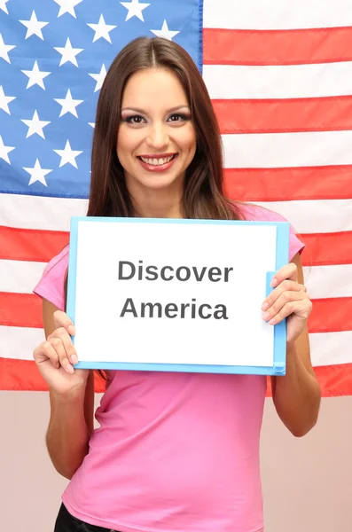 Mujer joven mujer joven sosteniendo tableta en el fondo de la bandera estadounidense — Foto de Stock