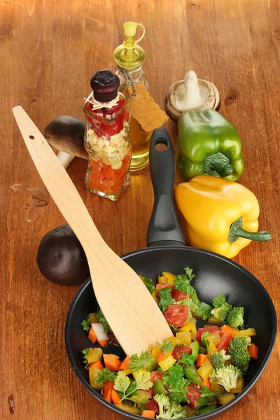 Sliced fresh vegetables in pan with spices and ingredients on wooden table — Stock Photo, Image