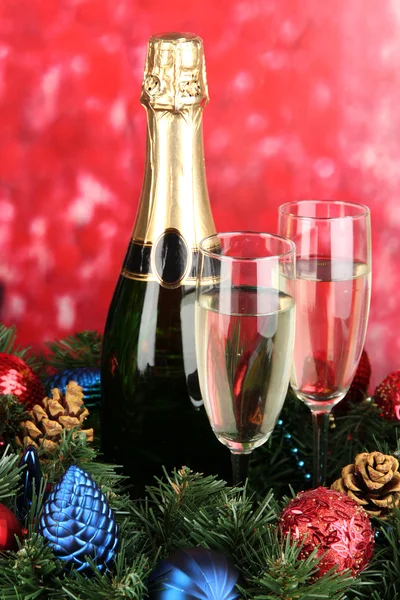 Beautiful Christmas wreath in composition with champagne on red background — Stock Photo, Image