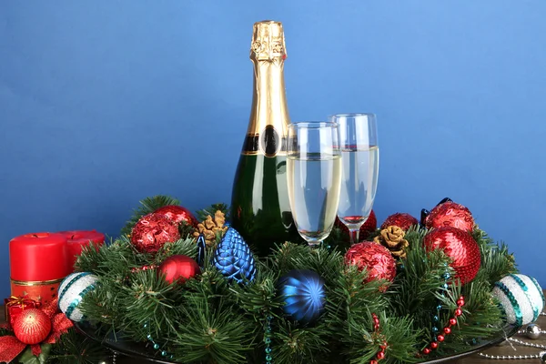 Schöner Weihnachtskranz in Komposition mit Champagner auf blauem Hintergrund — Stockfoto