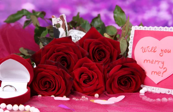 Mooi boeket rozen met valentine op roze stof op paarse achtergrond close-up Stockfoto