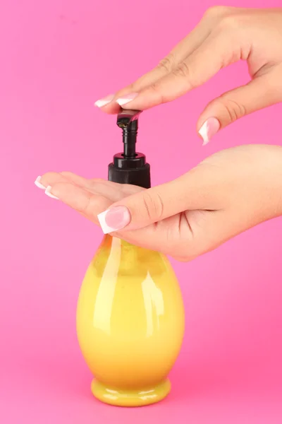 Woman squeezing lotion on her hand, on pink background close-up — Stock Photo, Image