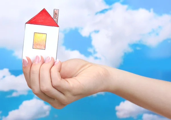 Koncepcja: ręka kobiety z domu papieru na tle nieba, z bliska — Zdjęcie stockowe