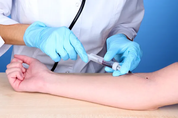 Enfermera toma sangre de las venas sobre fondo azul — Foto de Stock