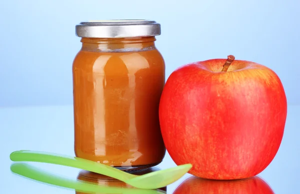 Nützliche und leckere Babynahrung mit Apfel und Löffel auf blauem Hintergrund — Stockfoto