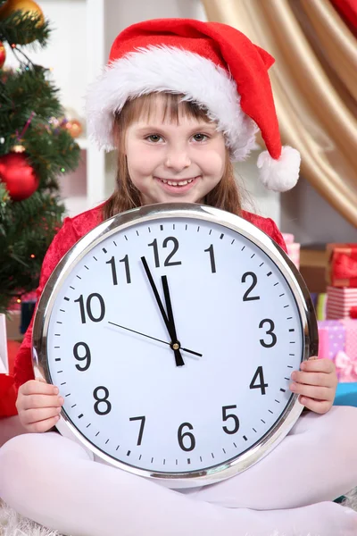 Bella bambina con orologio in previsione del nuovo anno in camera decorata a festa — Foto Stock