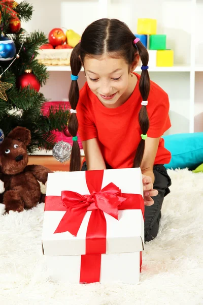 Kleines Mädchen mit Geschenkbox in der Nähe des Weihnachtsbaums — Stockfoto