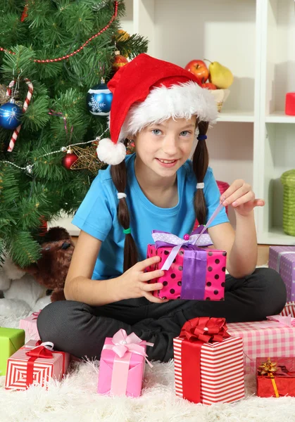 Klein meisje houden de doos van de gift in de buurt van de kerstboom — Stockfoto