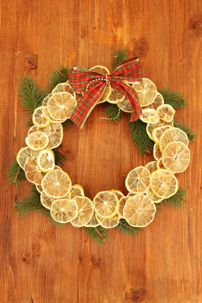 Corona de Navidad de limones secos con abeto y arco, sobre fondo de madera —  Fotos de Stock