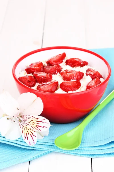 Cottage cheese in red bowl with sliced strawberries on white wooden table — Stock Photo, Image