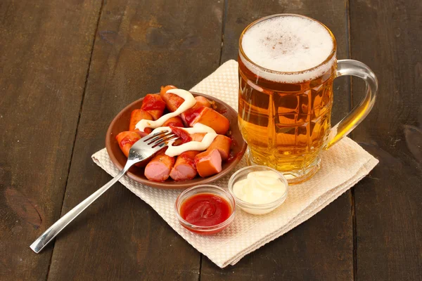 Cerveza y embutidos a la parrilla sobre fondo de madera —  Fotos de Stock