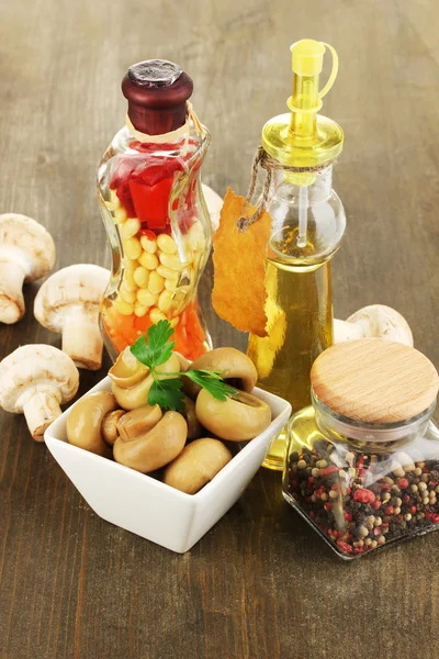 Delicious marinated mushrooms in bowl with spices on wooden table — Stock Photo, Image