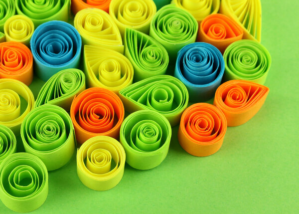 Colorful quilling on green background close-up