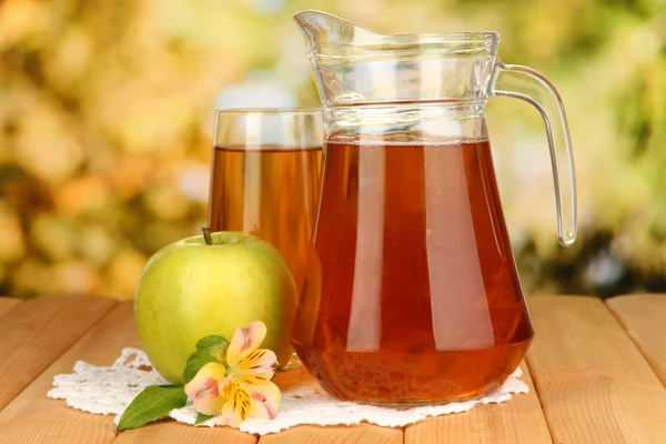 Copo completo e jarro de suco de maçã e maçã na mesa de madeira ao ar livre — Fotografia de Stock