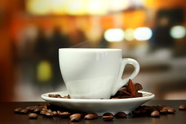 Cup of coffee with beans on table in cafe — Stock Photo, Image