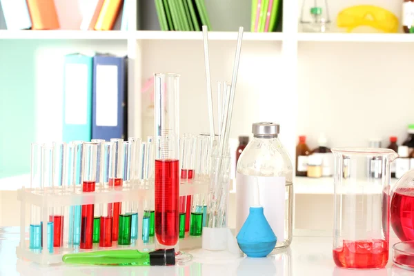 Различные лабораторные стекла с цветной жидкостью на лабораторном фоне — стоковое фото