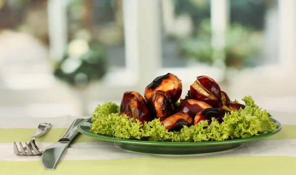 Roasted chestnuts with lettuce in the plate on the tablecloth close-up — Stock Photo, Image