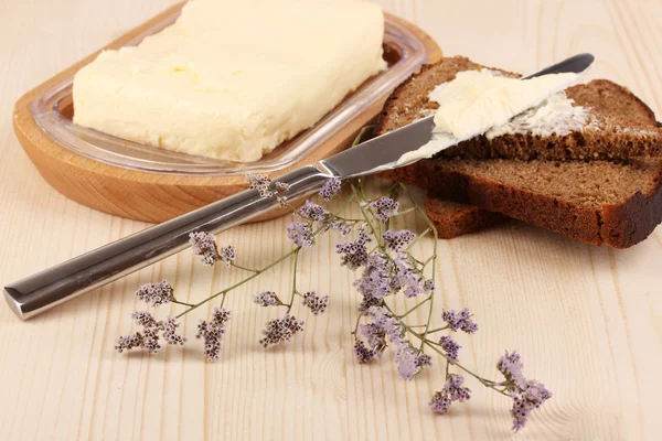 Smör på trä hållare och bröd på träbord närbild — Stockfoto