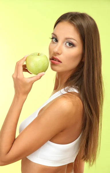 Beautiful young woman with green apple, on green background — Stock Photo, Image