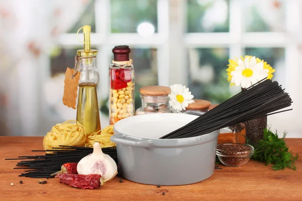 Spaghetti in pan on wooden table on bright background — Stock Photo, Image