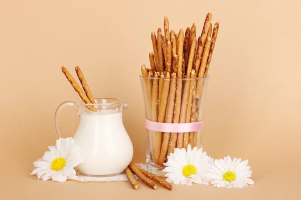 Tasty crispy sticks in glass cup on beige background — Stock Photo, Image