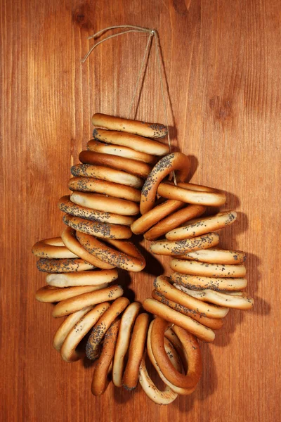 Tasty bagels on rope, on wooden background — Stock Photo, Image