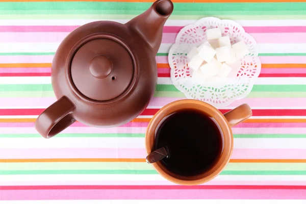 Top view of cup of tea and teapot on colorful tablecloths — Stock Photo, Image