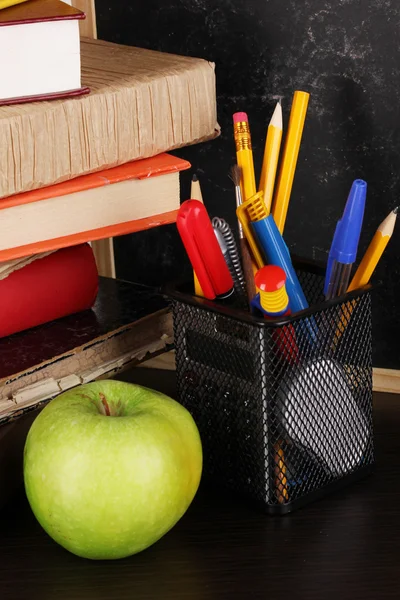 Libros y gorra magister contra pizarra escolar en mesa de madera de primer plano —  Fotos de Stock