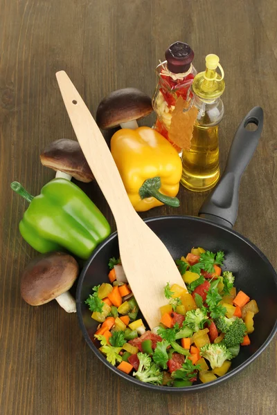 Legumes frescos fatiados em panela com especiarias e ingredientes em mesa de madeira — Fotografia de Stock