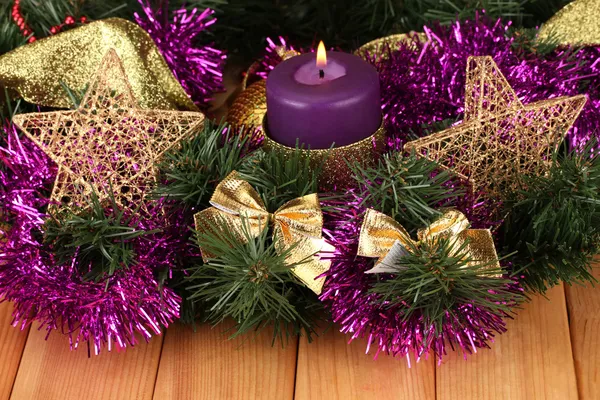 Рождественская композиция со свечами и украшениями в фиолетовых и золотых тонах на деревянном фоне — стоковое фото