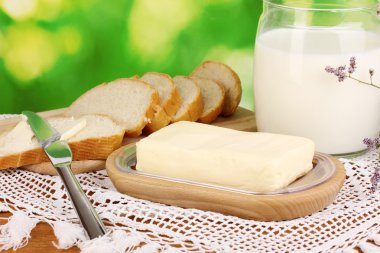 Doğal arka planda ekmek ve sütle çevrili ahşap tutacağa tereyağı.
