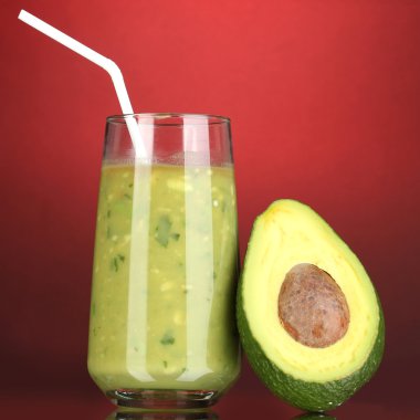 koyu kırmızı zemin üzerine yarım avokado ve faydalı taze avokado