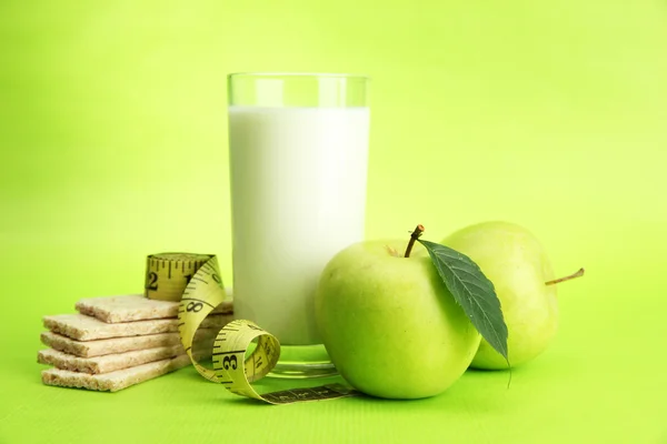 Bicchiere di kefir, mela, pane croccante e nastro adesivo, su fondo verde — Foto Stock