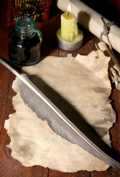 Papel viejo con pluma de tinta cerca de la vela de iluminación en la mesa de madera — Foto de Stock