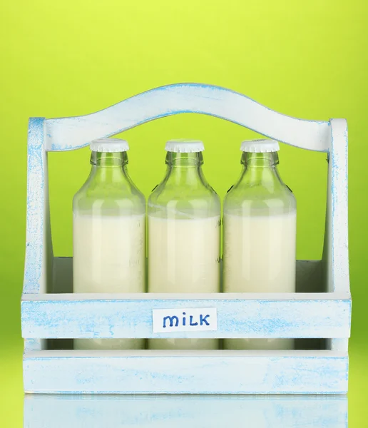 Γάλα σε μπουκάλια σε ξύλινο κουτί σε πράσινο φόντο — Φωτογραφία Αρχείου