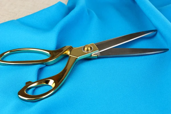 Metal scissors on blue fabric — Stock Photo, Image